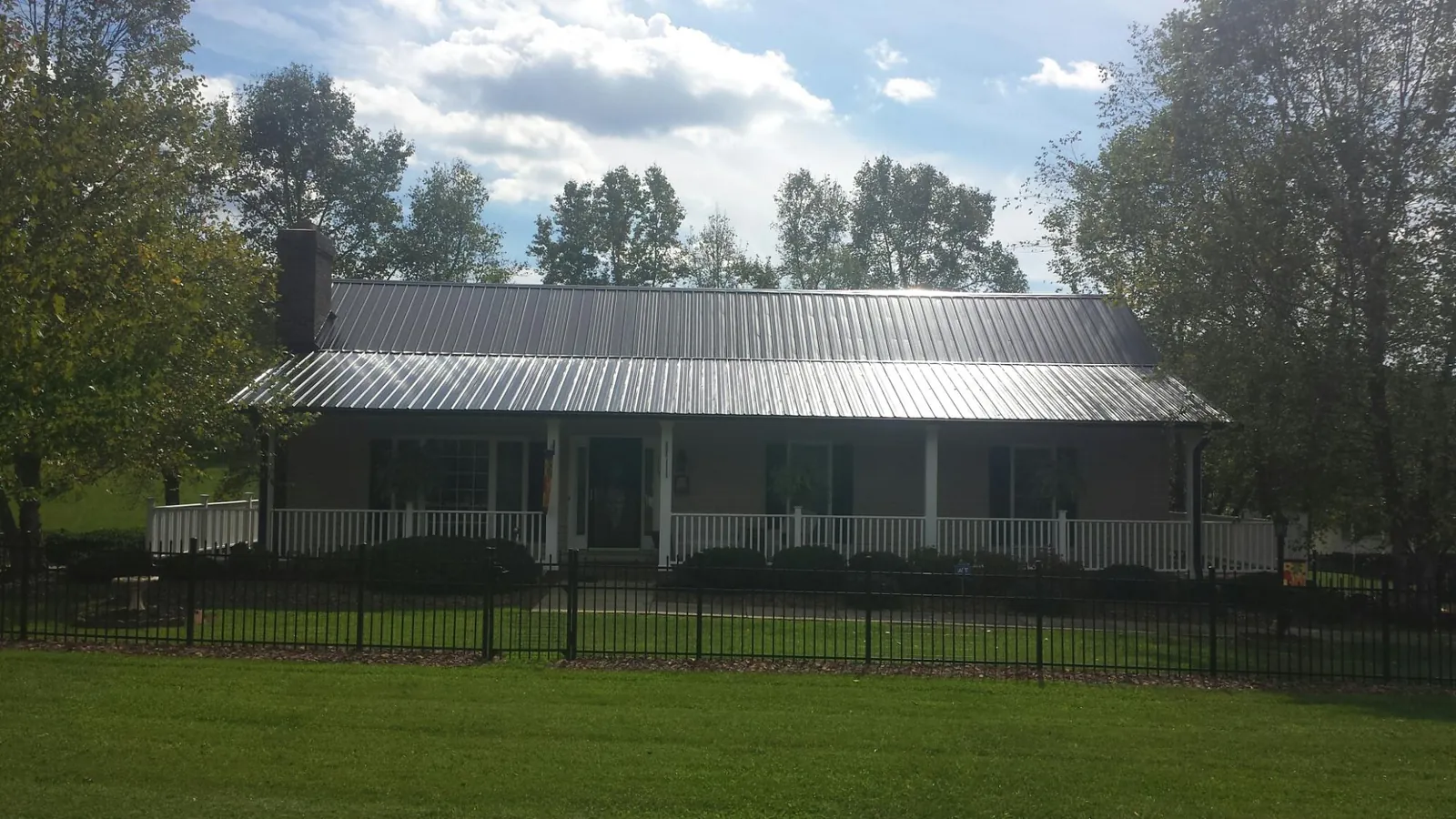 Gray metal roof on a brick ranch with a full width front porch — Gutter Guard Installation work by our crew in North Fort Myers