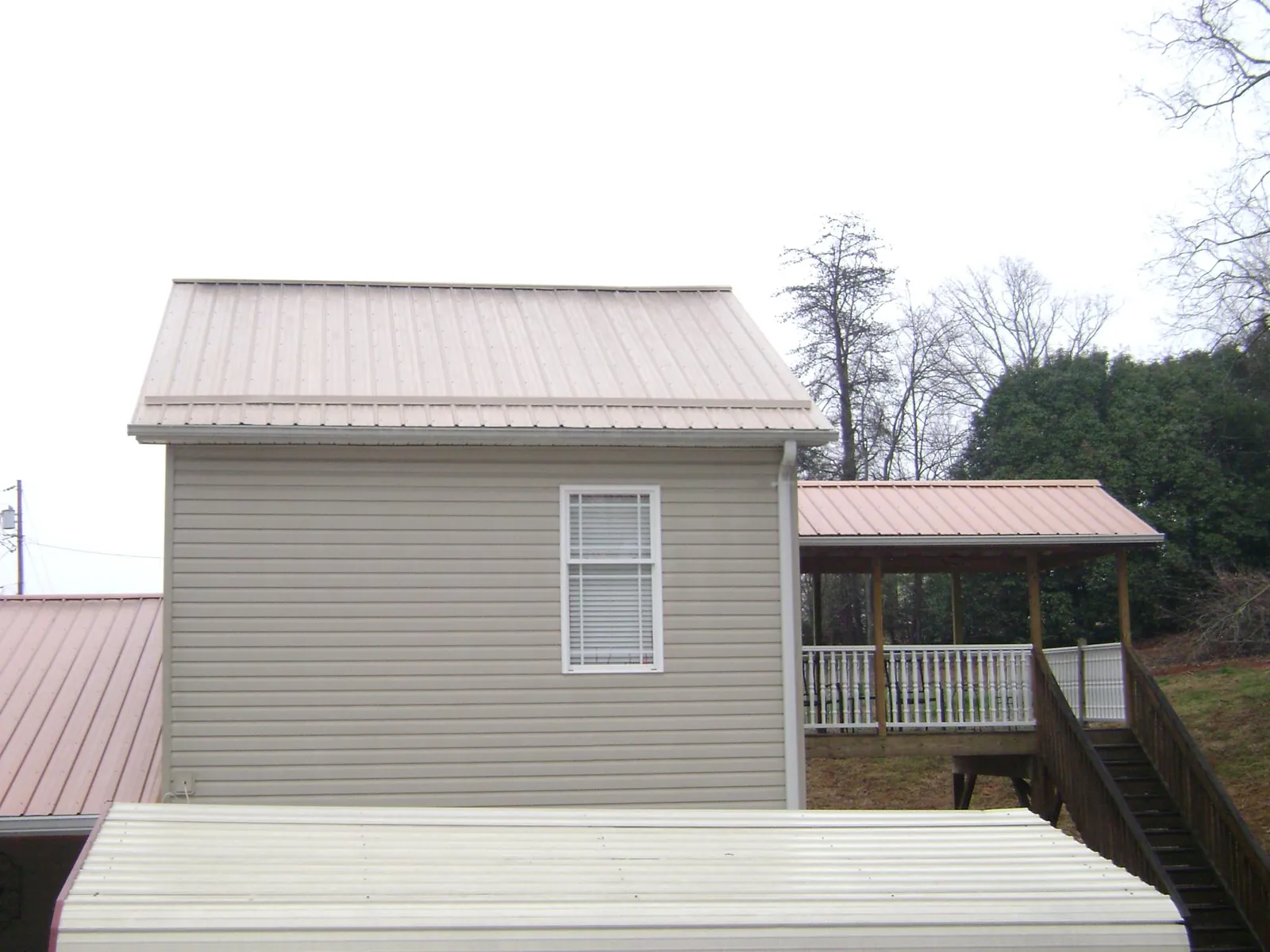 Tan metal roofs on a two story addition and attached porch, from a Roof Replacement job in North Fort Myers