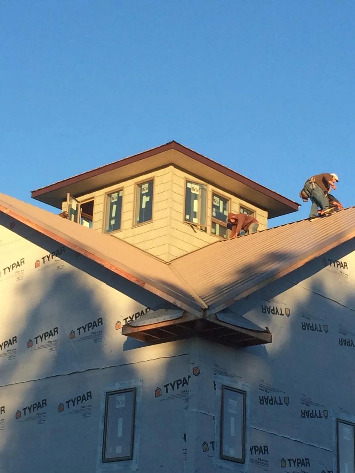 Roofers working around a rooftop cupola on a new metal roof at sunset — Roof Waterproofing in North Fort Myers by Roofing Brothers
